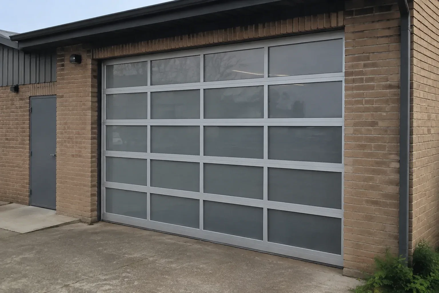 Closed glazed sectional door in a grey metal frame at a brick workshop. — Full-View Glass Garage Door Installation, Richmond Hill